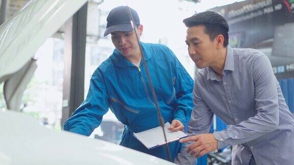 亚洲汽车技师在车库里向客户讲解汽车状况车辆维修经理男在机械车间工作负责车辆零部件的维修工作