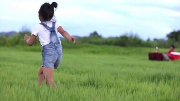 亚洲的小女孩和父亲带着风筝在夏季的草地上奔跑和快乐的大自然中慢镜头