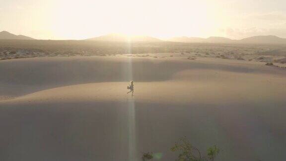 无人机拍摄到一个女人在日落时分独自行走在沙漠中