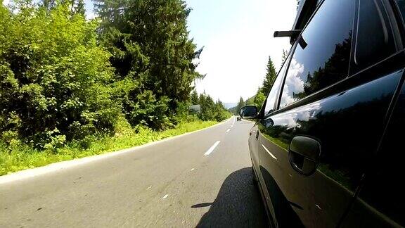 绿色汽车行驶在良好的道路在农村地区的木材