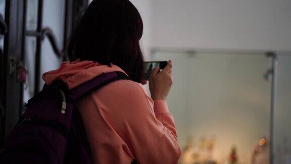 年轻女子戴医用口罩的特写镜头在智能手机上拍照女游客在公共场所用手机拍照