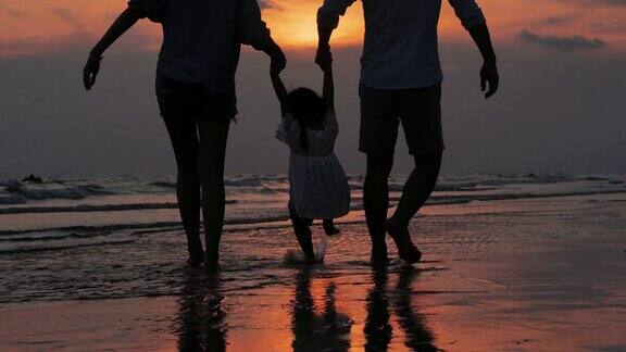 幸福的一家人在海滩上散步的剪影快乐的一家人在海滩上享受暑假假期iStock