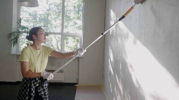 一名日本妇女在家用油漆滚筒刷墙
