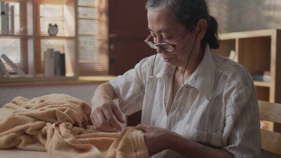 资深退休亚洲女性喜欢缝纫和编织在公寓