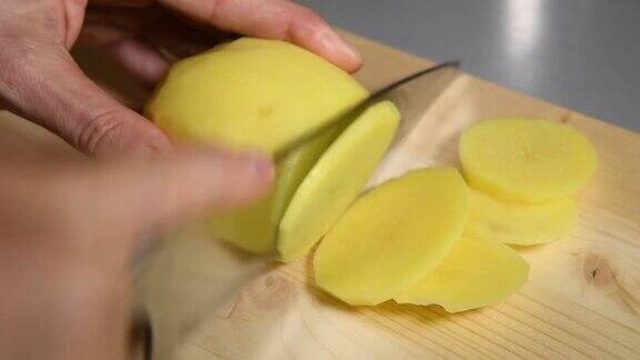 女性的手在砧板上用刀切土豆