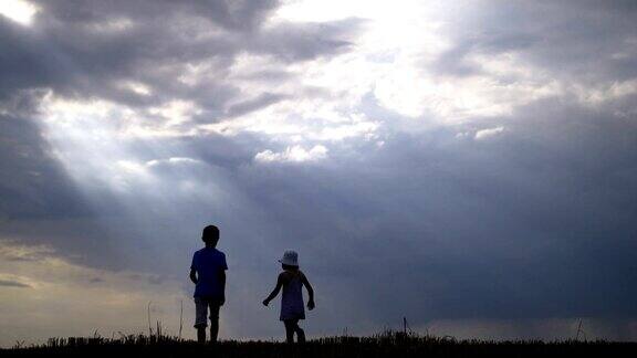 男孩和女孩走在一起手牵着手在一个云彩的背景在早晨