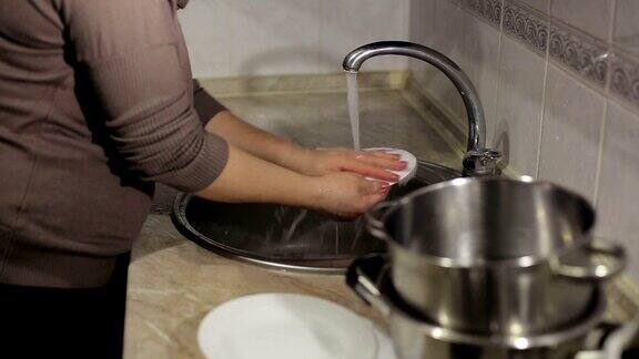 一个年轻女子在家里的水槽里洗盘子