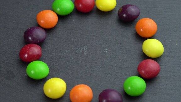 彩色糖果在黑色背景上旋转手拿一颗糖果彩色糖果