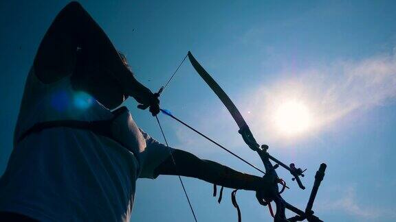弓箭手在阳光下拉弓用弓和箭射击