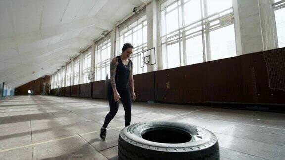 强壮的女运动员与轮胎训练