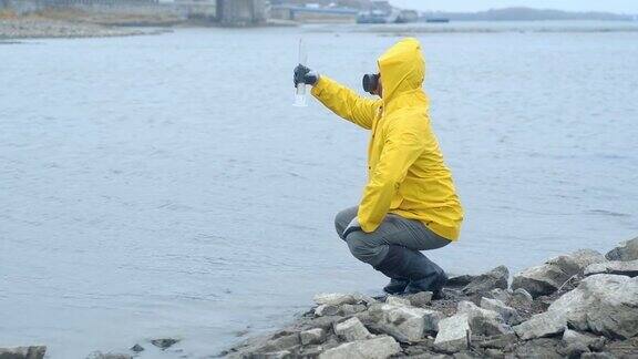 穿着黄色雨衣的生态学家从河里把水注入一个试管