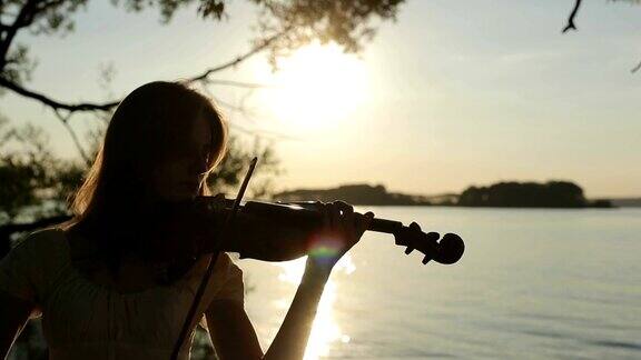 日落时分女小提琴家在湖边拉小提琴