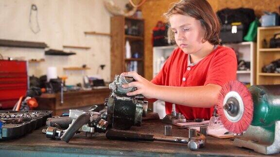 一个十岁的男孩在家庭作坊里修理他的摩托车引擎
