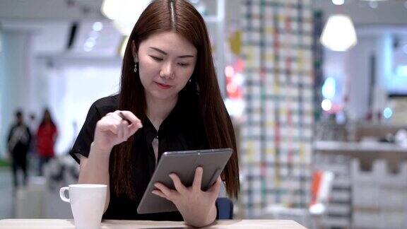 一个女人在咖啡店里用笔记本电脑工作一边看一边思考解决问题