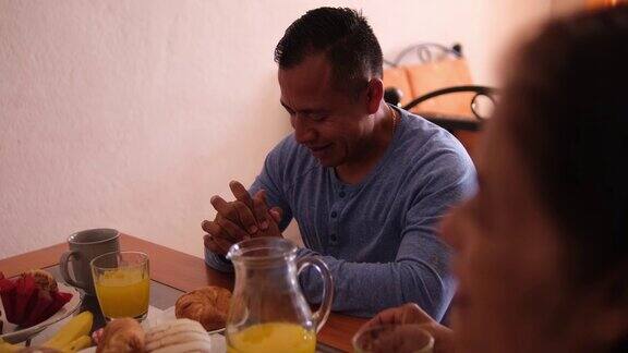 拉丁家庭在家里吃早餐前祈祷