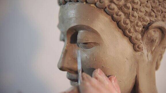 泥塑佛像的人像面艺术家用刮刀打磨细节