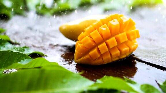 新鲜的黄色芒果热带水果切片与雨滴在木桌上