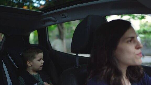 母亲开车而她的儿子坐在汽车安全座椅上
