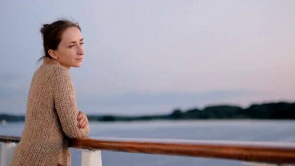 日落后从游轮甲板上欣赏风景的女人