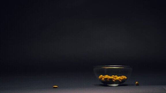 黄色糖果在玻璃碗中缓慢下落复制空间在黑色黑板纹理背景上