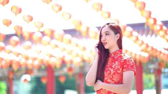 亚洲美女身穿红色中国传统旗袍用手机装饰中国新年主题