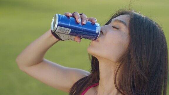 年轻女子喝能量饮料亚洲女人喝汽水罐