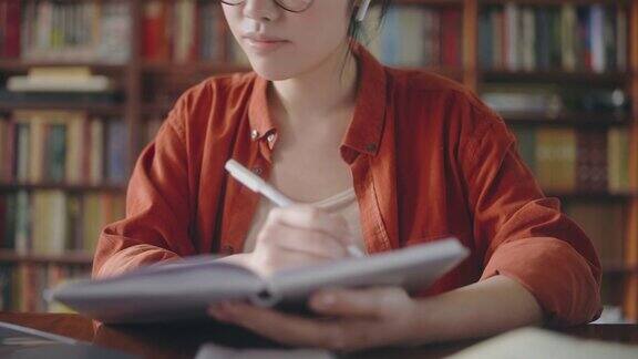 勤奋的亚洲学生在网上上课做笔记坐在图书馆
