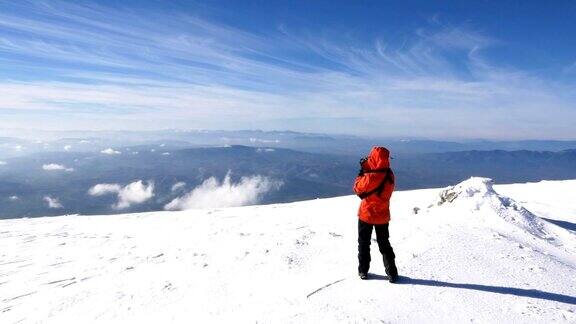冬季女性高山攀登者在高海拔的山峰上拍照