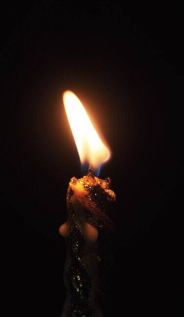 垂直视频一支蜡烛点燃在黑色的背景黑暗中的烛光
