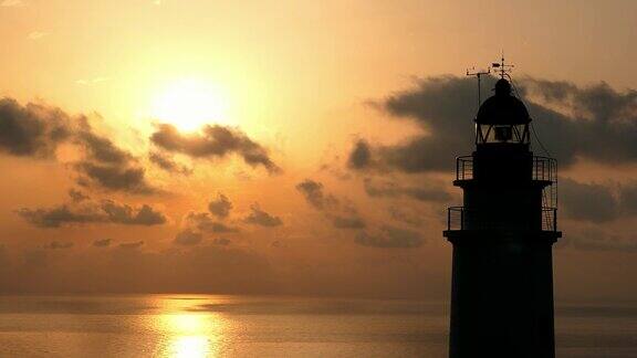 日出时马略卡岛上岩石悬崖上的灯塔和壮观的云彩