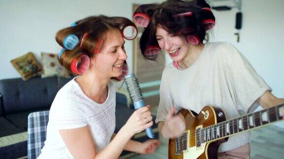 两个有趣的女孩用梳子唱歌弹电吉他跳舞唱歌在家里有快乐