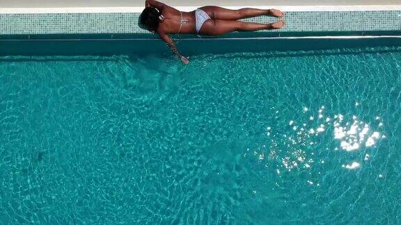 鸟瞰图一个女人日光浴的无边泳池