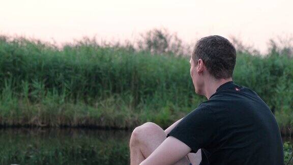 日落时分平静放松的人坐在湖岸上在很多鱼竿上钓鱼