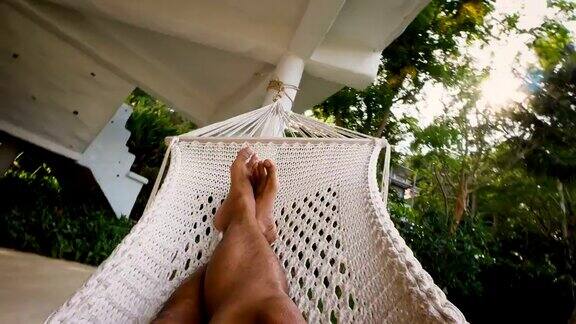 一名年轻人在泰国热带度假胜地的吊床上休息