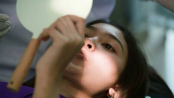 亚洲年轻女性照镜子检查脸和牙齿矫正治疗