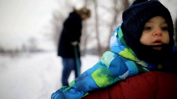 一个年轻人在冬季森林里拉着他们的儿子和妻子的雪橇