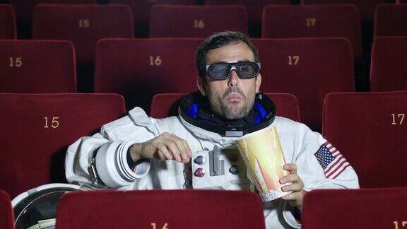 一名宇航员一边看电影一边吃着爆米花享受着电影的乐趣概念:电影和太空电影电影的另一个世界超现实的情况