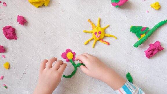 小女孩的手用五颜六色的粘土面团、橡皮泥等制作花朵和太阳