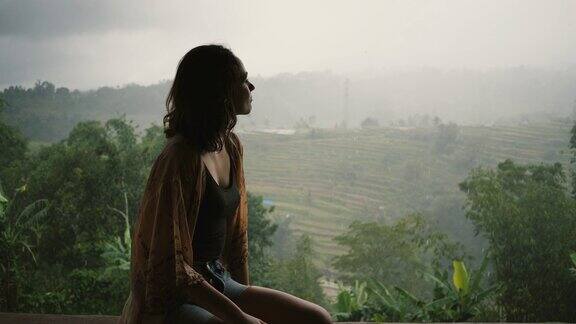 在巴厘岛看雨下的丛林的女人