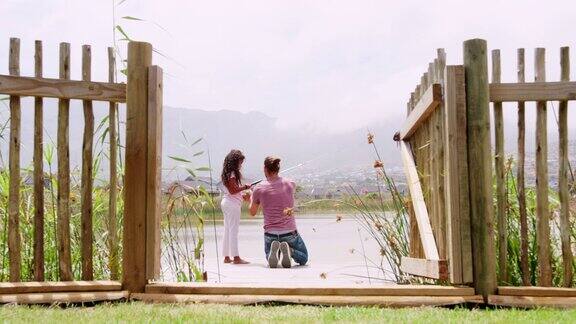 父亲和女儿在湖中钓鱼从木制码头后视图