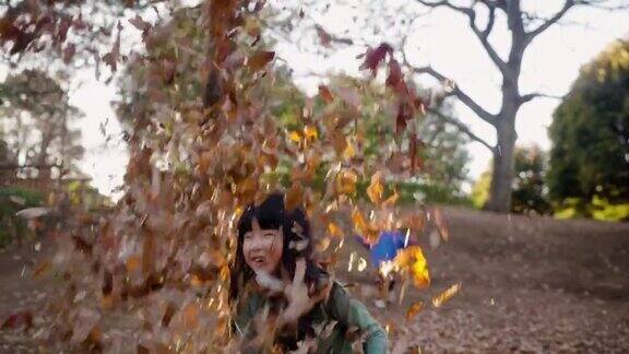 小女孩在公园里玩落叶
