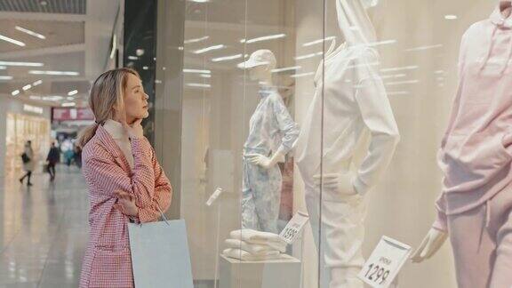 时尚女性在看服装商店的橱窗展示