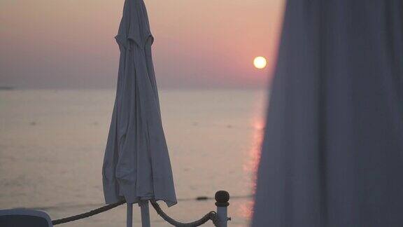 红红的夕阳倒映在大海或大海里躲在沙滩伞后面东方国家的日落土耳其美丽的自然风光
