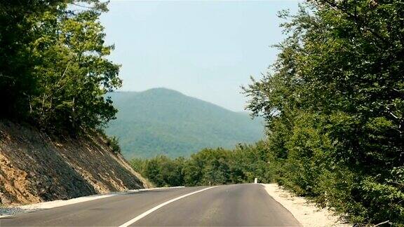 在山路上驾车穿过森林在山上一个晴朗的夏日里在空旷的路上开车