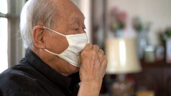 年长的亚洲人戴着口罩在家咳嗽