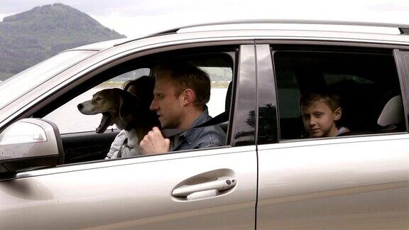 妈妈、爸爸、儿子和比格犬坐在车里系好安全带出发去旅行