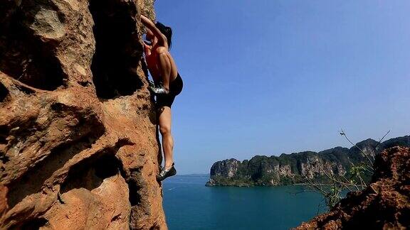 年轻女子攀登岩石海边