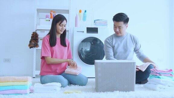 年轻夫妇在家里一起用自动洗衣机洗衣服和毛巾他们一起愉快地把家里打扫干净