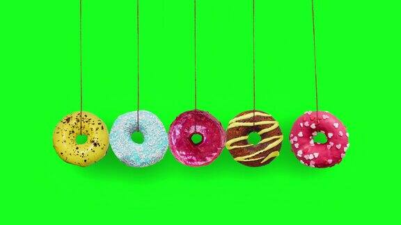 彩色的甜甜圈摆动作为一个牛顿的摇篮在色度键的背景