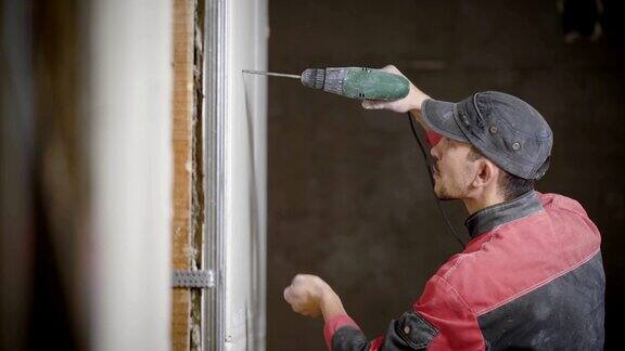 一名专业的建筑工将钉子钉进石膏制成的墙壁以连接金属框架和石膏
